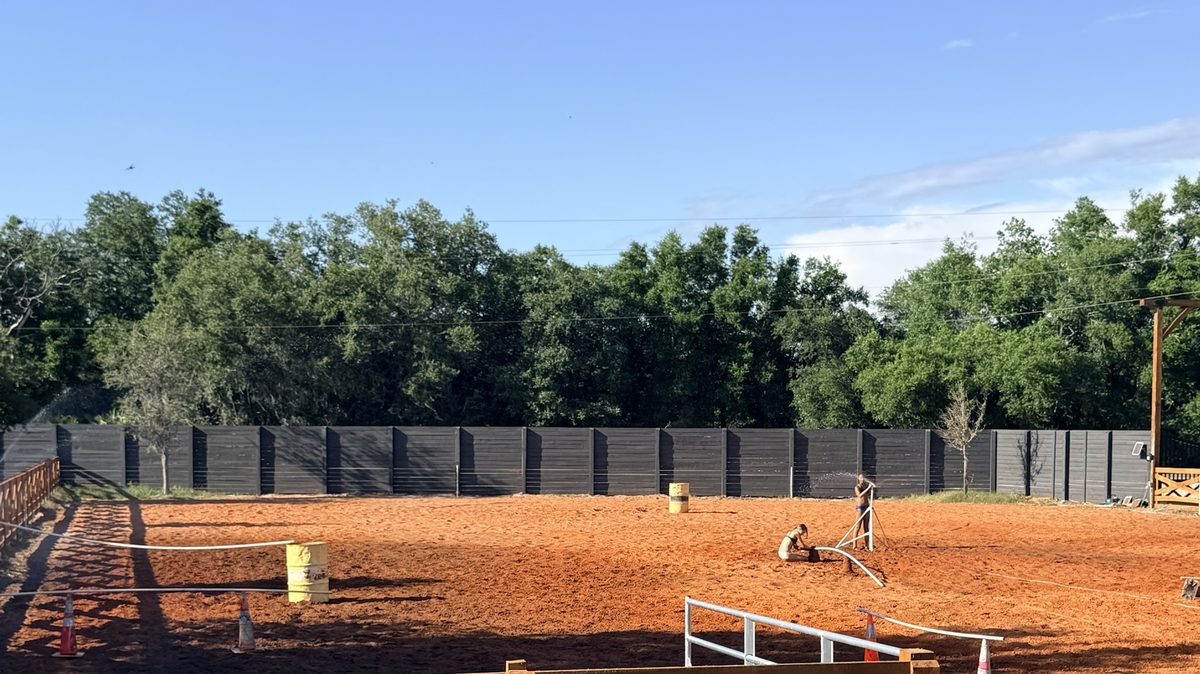 Graded riding arena with wood rail fencing and footing built by Eco Equine