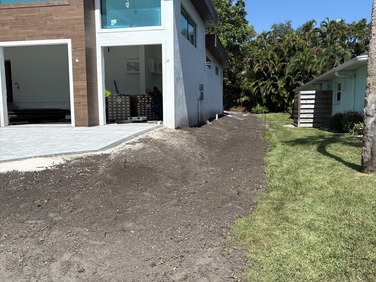 Driveway area cut and graded beside a modern new-build home