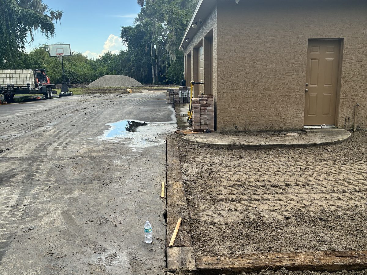 Shell and rock base pad laid and graded next to a building
